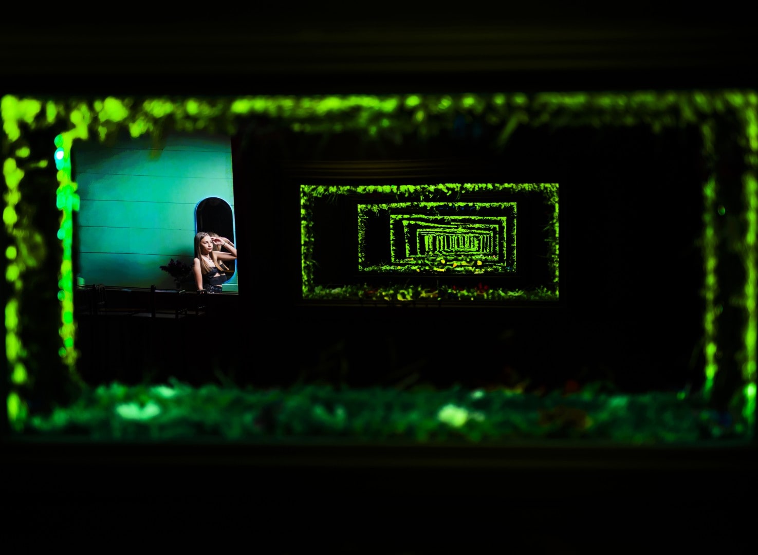 Retrato nocturno enmarcado por un cerco de follaje iluminado en verde